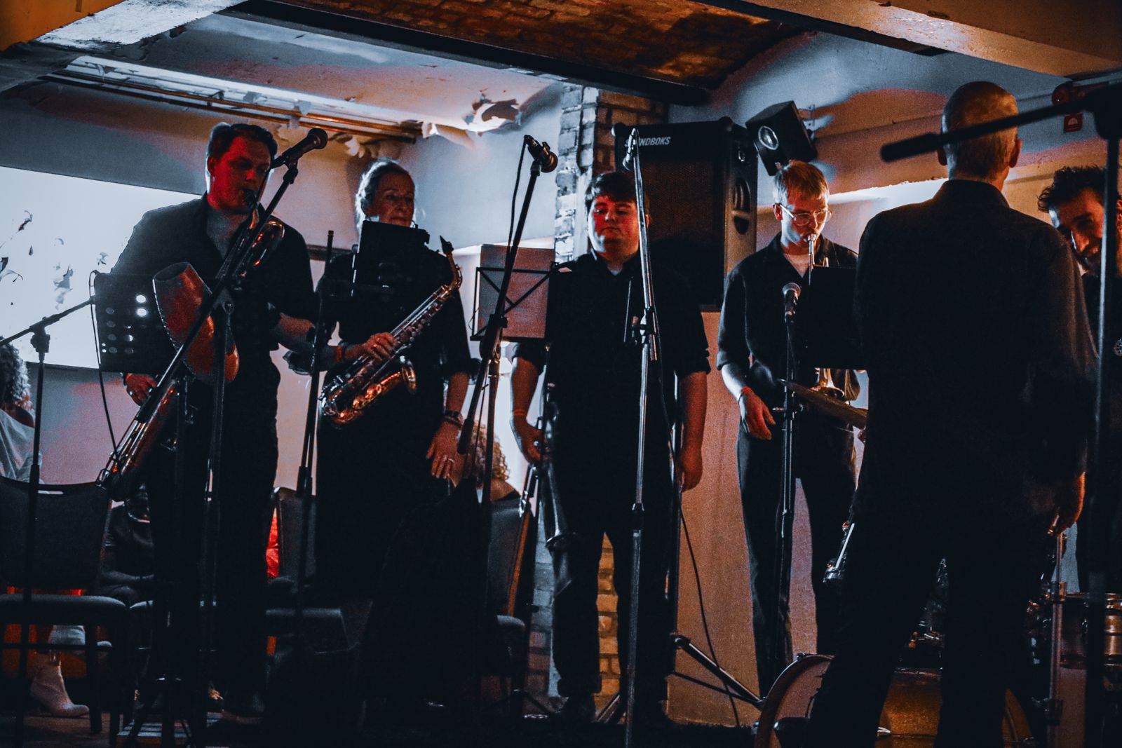 Horn section of JL Son de Armonía playing live in a brick-vaulted venue